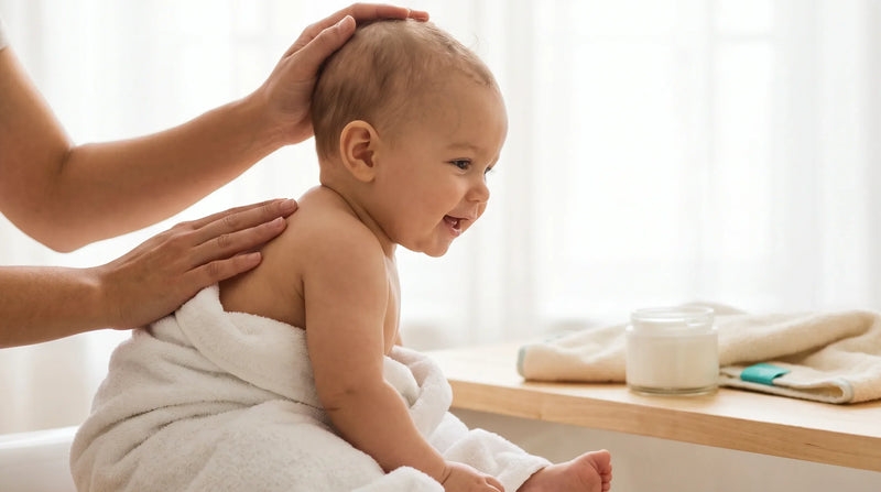 Calm baby being patted dry after a bath with a fragrance-free remedy jar nearby for eczema in infants natural remedies
